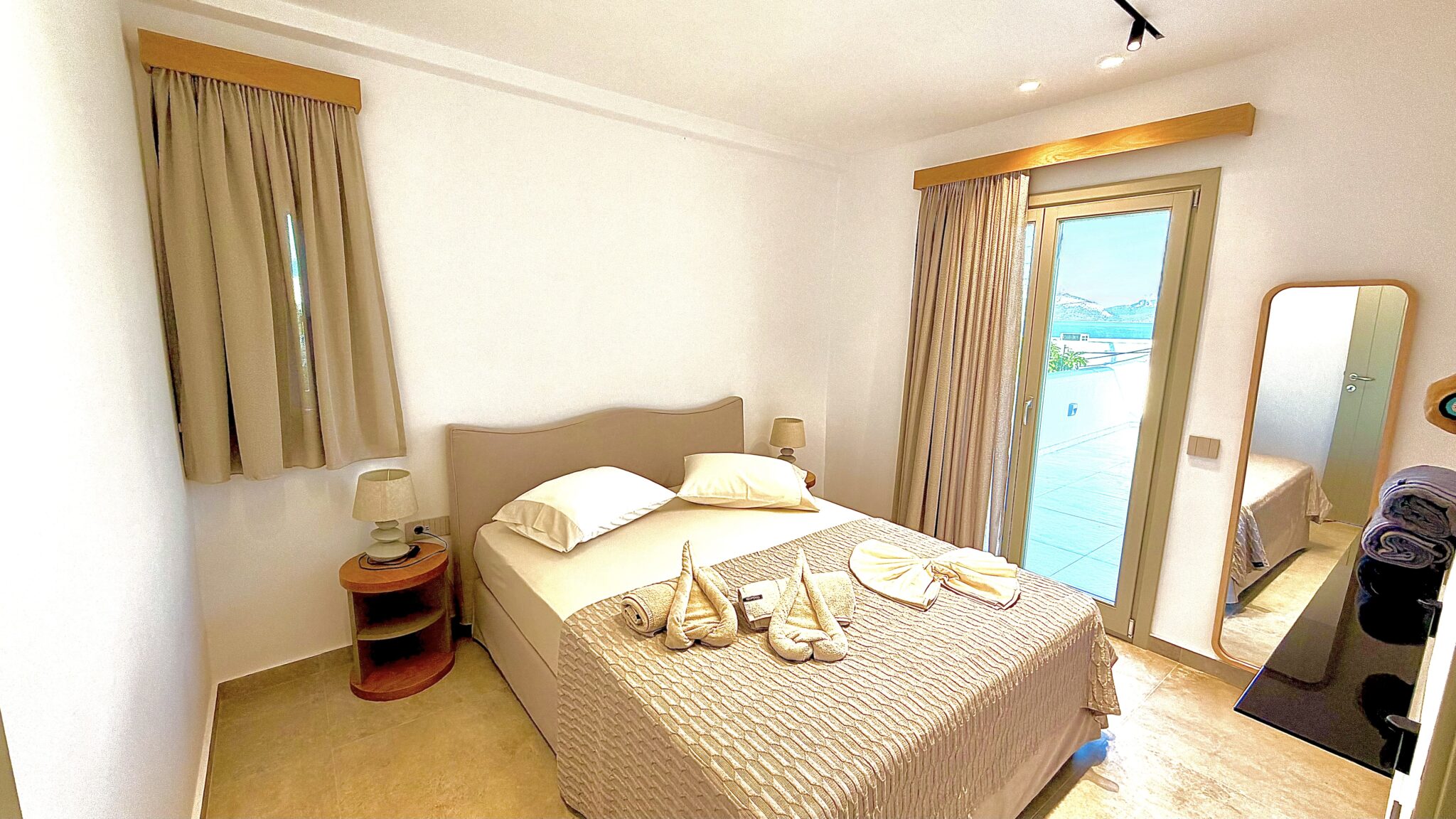 Suite with Jacuzzi – king-size bed with folded towels and view to the terrace